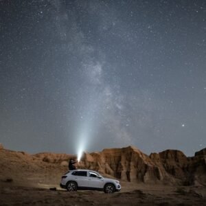 Desert Wilderness - A person stands on an SUV under a vast starry ni #3064258